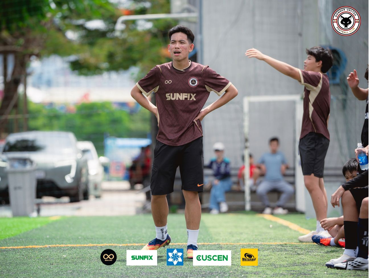A Gonner United FC player in the maroon and gold kit stands with his hands on his hips during a match