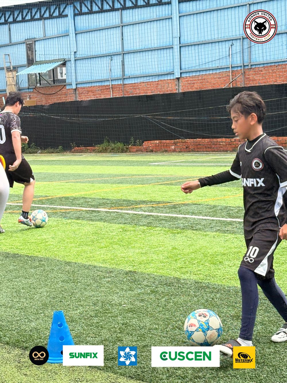 A Gonner United FC player in the black kit dribbles past a blue cone during a training drill