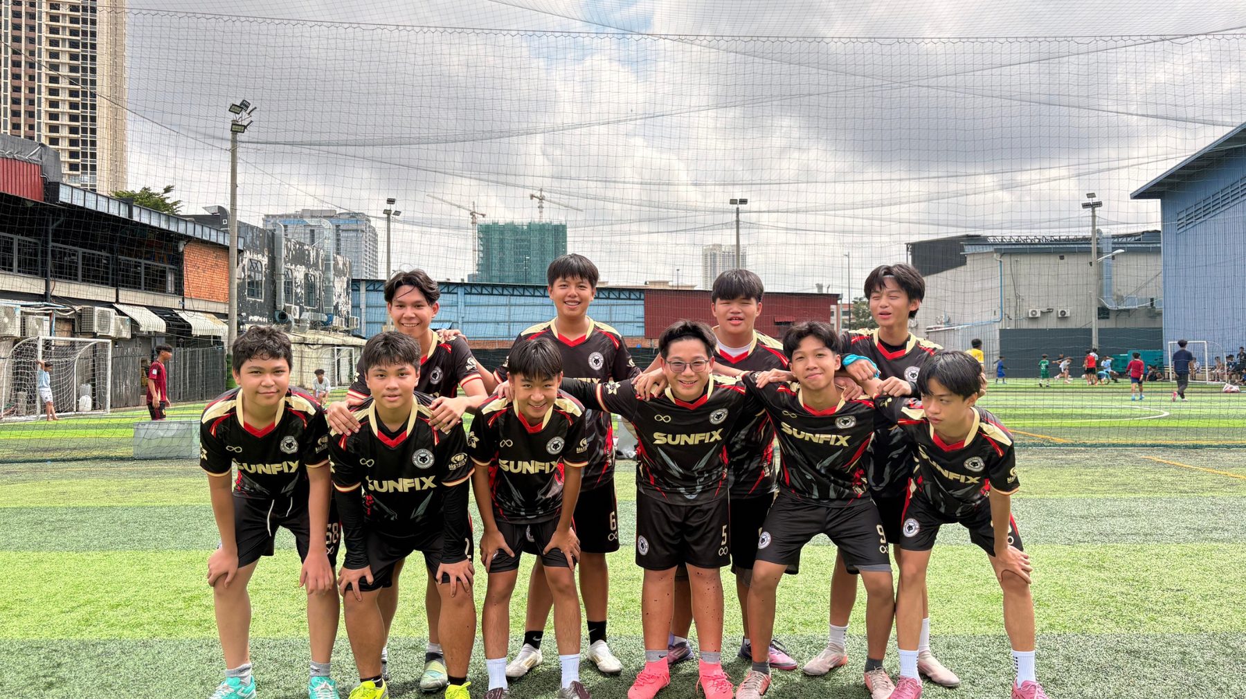 Gonner United FC players in the black, red and gold kit, arms around each other on the pitch